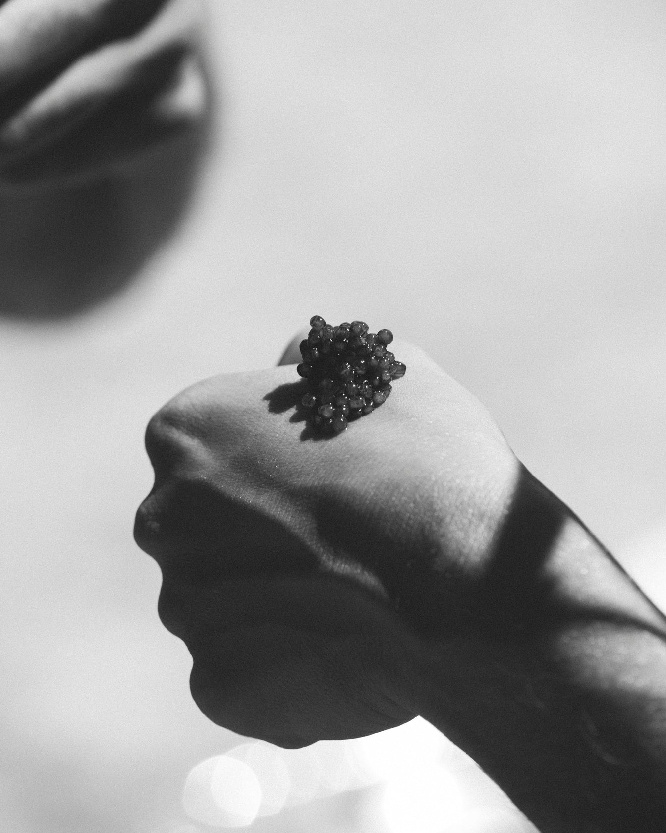 Close-up of caviar pearls on hand in a tasting presentation
